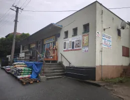 Prodejna Voda v zahradě zvenku, vstup po schodech a zboží složené u zdi